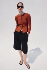 Chaqueta de punto color óxido, con cuello redondo, manga larga abullonada y cierre frontal con botones.