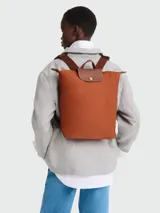 Mochila Longchamp modelo Le Pliage Original en tamaño M, color terracota. Confeccionada en nylon resistente con solapa y correas de cuero marrón, cierre superior con cremallera y botón a presión metálico.