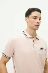 Remera polo azul marino de manga corta, con cuello y puños a rayas blancas y verde militar. Presenta un bolsillo en el pecho con detalle de franja a rayas y el logo de la marca "Brooksfield" bordado en dorado.