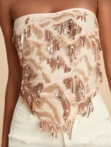 Top strapless color beige con bordados de lentejuelas y canutillos en tonos dorados y rosados, formando un patrón de flecos.