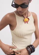Top de punto fino color beige, con cuello barco y tirantes finos, de diseño entallado y sin mangas.