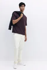 Jogger color blanco hueso en tejido suave de mezcla de algodón, con pliegue cosido en la parte delantera. Presenta cierre decorativo, cintura elástica con cordón ajustable, bolsillos laterales y un bolsillo insertado en la parte trasera. Corte estándar.