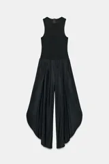 Mono largo negro con cuerpo de tejido ajustado sin mangas y cuello redondo, combinado con pantalón ancho de tejido fluido y satinado con diseño abullonado y bajo asimétrico. Cierre trasero con cremallera oculta.