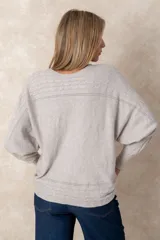 Buzo de punto color azul petróleo, con cuello redondo, mangas largas con puños ajustados y detalles de textura trenzada en la parte superior y el ruedo.