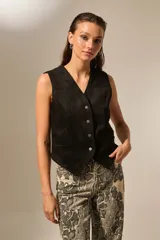 Chaleco de gamuza sintética color negro, con escote en V, cierre frontal con botones metálicos y bolsillos laterales.