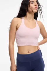 Top deportivo color rosa pálido, con escote en V y espalda tipo halter. Presenta un corte largo que llega hasta la cintura.
