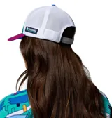 Gorra Columbia x Disney tipo trucker, con panel frontal de color verde, visera fucsia, paneles traseros de malla blanca y parche redondo con gráfico de Mickey Mouse practicando esquí. Incluye etiqueta lateral con el logo de Columbia y Disney.