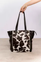 Bolso tipo tote confeccionado en cuero legítimo, con diseño amplio y práctico. Presenta un frente con estampado animal print con efecto pelaje, combinado con laterales y asas en cuero graneado negro.