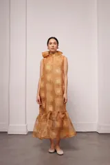 Vestido largo color ocre con estampado de cuadrados dorados, cuello alto y corte amplio. Incluye viso liso al tono.