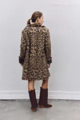 Tapado de piel sintética con estampado animal print de leopardo, corte recto y largo hasta la rodilla, con solapas clásicas y cierre frontal.