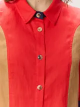 Camisa de lino color blanco con detalles combinados en tonos beige, cuello camisero, cierre frontal con botones oscuros y mangas largas con puños en contraste.