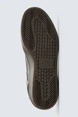 Zapatilla deportiva de estilo retro, color negro, con parte superior fabricada en combinación de piezas de cuero liso y gamuza perforada. Presenta una suela de goma en color marrón oscuro o ahumado en contraste.