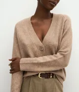 Cardigan de punto color beige con escote en V, cierre frontal con botones grandes y mangas largas con puños acanalados. Presenta un corte recto y estructurado.
