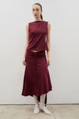 Falda midi de color bordó, con diseño de frunce central ajustable y ruedo irregular con volado lateral.