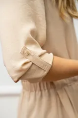 Camisa de seda color celeste, con cuello camisero, mangas largas y lazo ajustable en la cintura que genera un efecto fruncido.
