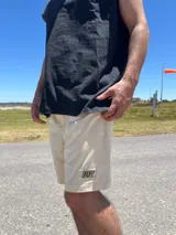 Bermuda de algodón color negro con calce relajado y cintura elastizada. Presenta un parche rectangular con el logo "DROPZ" en la parte inferior de la pierna izquierda y un largo por encima de la rodilla.