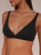 Soutien tipo halter confeccionado en algodón, con tirantes ajustables y detalle de ondas decorativas en los bordes.