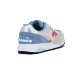 Championes deportivos Diadora modelo N902, con diseño multicolor que combina tonos celestes, beige, rosado y rojo. Presentan una estructura de paneles en gamuza y malla, con el logo característico de la marca en el lateral y suela de goma con entresuela blanca.