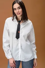 Camisa blanca de corte oversize, con cuello clásico, cierre frontal de botones y mangas largas con puños abotonados.