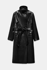 Trench de corte largo confeccionado en piel 100% con acabado brillante. Presenta cuello alto, hombreras marcadas, manga larga, bolsillos con solapa en el delantero y cierre frontal con botones. Incluye un cinturón ajustable del mismo material para entallar la silueta.