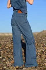 Pantalón de jean tiro alto con corte recto y holgado, confeccionado en denim azul con estampado de motivos naturales en tono azul oscuro.