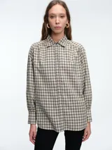 Camisa de corte clásico con estampado de cuadros en tonos neutros, cuello camisero, cierre frontal con botones y mangas largas con puños abotonados.