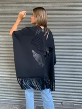 Ruana negra con apliques de cuero y flecos.