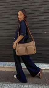 Bandolera de tafeta impermeable color beige, con dos bolsillos frontales con cierre y correa regulable. Diseño práctico y liviano ideal para uso diario.