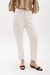 Jean gris lavado, estilo mom fit, con aplique fruncido en forma de espiral en la pierna izquierda, tiro alto, bolsillos delanteros y traseros funcionales, y cierre frontal con botón y cremallera.