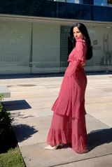 Vestido largo de fiesta color rosa viejo, con cuello alto, mangas largas con volados en los puños y falda con volados escalonados. Presenta una cintura elástica fruncida que define la silueta.