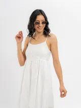 Vestido midi de broderie color blanco, con tirantes finos, escote recto y detalle de botones frontales decorativos.