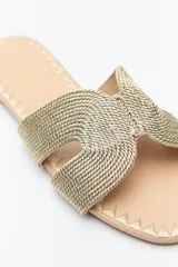 Sandalia baja dorada con capellada trenzada tipo cordón y suela con bordado a tono.