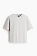 Remera boxy de punto de algodón pesado, color gris claro, con cuello redondo ribeteado acanalado, hombros caídos y mangas cortas de corte holgado.