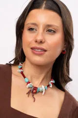 Collar corto elaborado con cuentas de turquesa reconstituida, piezas de nácar blanco, cuentas de cristal rojo y turquesa, y un dije central con forma de rama de coral.