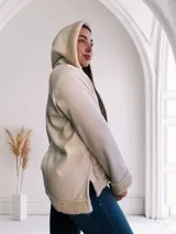 Campera de pana color crema con interior de piel sintética color beige. Tiene capucha, cierre con botones a presión, bolsillos laterales y puños con ribete de piel sintética.