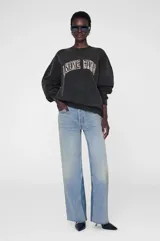 Buzo oversized de cuello redondo, confeccionado en algodón fleece con interior cepillado. Presenta un diseño de lavado gastado en color negro y estampa frontal con tipografía universitaria con relleno de animal print.