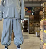 Pantalón deportivo de corte holgado en color verde musgo, con tiro alto, bolsillos laterales y puños elásticos en los tobillos. Presenta costuras verticales decorativas en el frente de cada pierna.