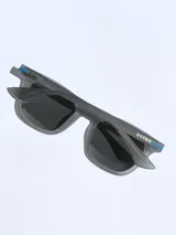 Lentes de sol con armazón de color gris mate y detalles en azul en las patillas. Cuentan con cristales oscuros polarizados y protección UV 400.
