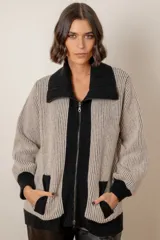 Campera de punto tipo cárdigan con cierre frontal de doble cursor, confeccionada en lana. Presenta un diseño bicolor con cuerpo en tono gris claro y detalles en azul marino en el cuello, la franja central, los bolsillos y los puños. Posee mangas largas con terminación ajustada y bolsillos frontales.