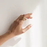 Anillo de diseño abierto con estructura de rejilla entrelazada, elaborado artesanalmente en metal con acabado plateado.