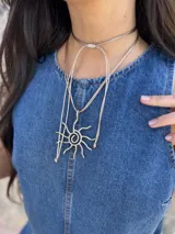 Collar con cordón ajustable color beige y dije de sol plateado.