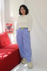 Pantalón de corte holgado y estilo relajado, color lila, con cintura elástica y un aplique decorativo de acrílico en el frente.