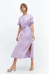 Vestido midi color coral confeccionado en lino. Tiene corte recto, mangas abullonadas con detalle de tablas en el puño, tajos laterales y lazo en la cintura.