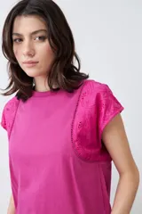 Remera fucsia de algodón con mangas cortas que presentan detalles de broderie y costuras decorativas.