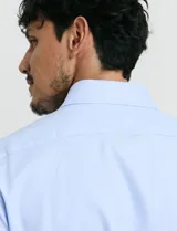 Camisa de vestir de manga larga en color celeste, con cuello clásico y cierre frontal de botones.