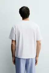 Set de pijama para hombre compuesto por una remera blanca de cuello redondo y mangas cortas, y un pantalón celeste a rayas verticales con cintura elástica y bolsillos laterales.