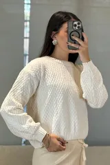 Buzo de tejido chenille con textura en relieve, cuello redondo y mangas largas con puños ajustados.