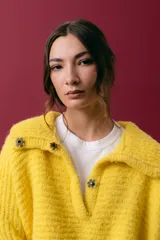 Buzo tejido en mohair de color gris, con silueta amplia y corte en línea A. Presenta cuello tipo remera con broches que permiten cerrarlo como polera, mangas largas con puños y un diseño de tejido horizontal.