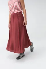 Falda larga beige de corte evasé, con diseño fluido y detalles de costuras verticales en la parte delantera.