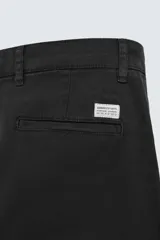Pantalón chino de corte ajustado, color beige, con bolsillos laterales y bolsillos traseros de vivo. Cuenta con cierre frontal de cremallera y botón.